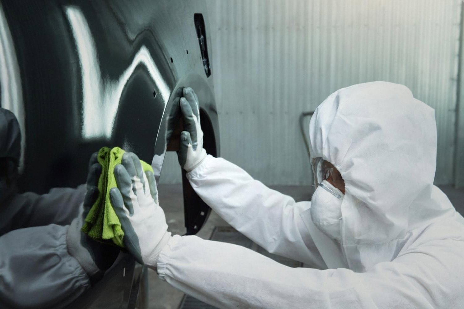 Bodywork specialist polishing a repaired car panel inside a UAE paint booth