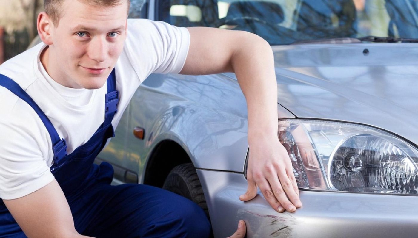 UAE workshop technician inspecting a deep scratch on a silver car bumper