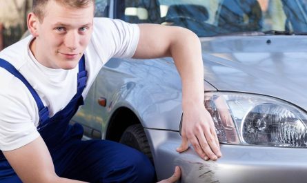 UAE workshop technician inspecting a deep scratch on a silver car bumper