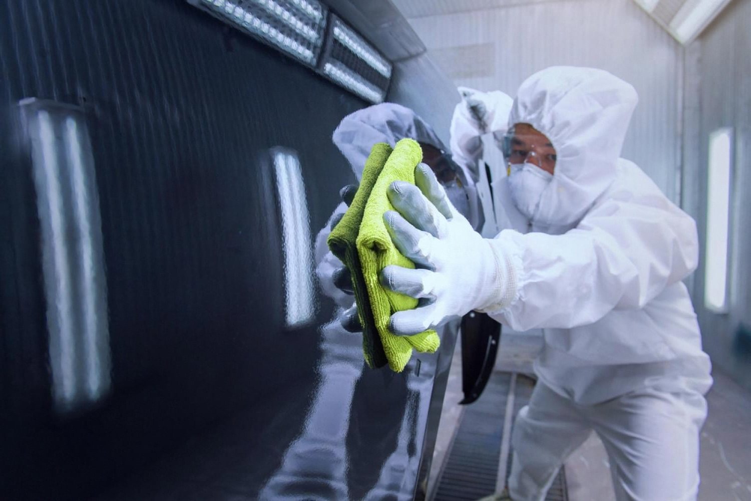Detailer wiping sand and dust residue off a car panel after a sandstorm